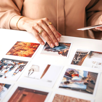 Mano arreglando fotografías impresas sobre una mesa blanca