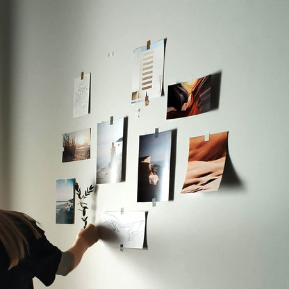 Persona poniendo fotografías y dibujos en una pared