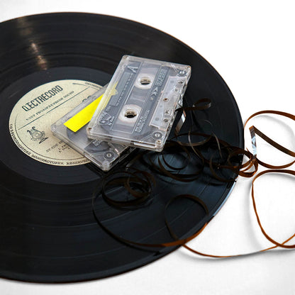 Disco de vinilo con casetes de audio y cinta deshilada